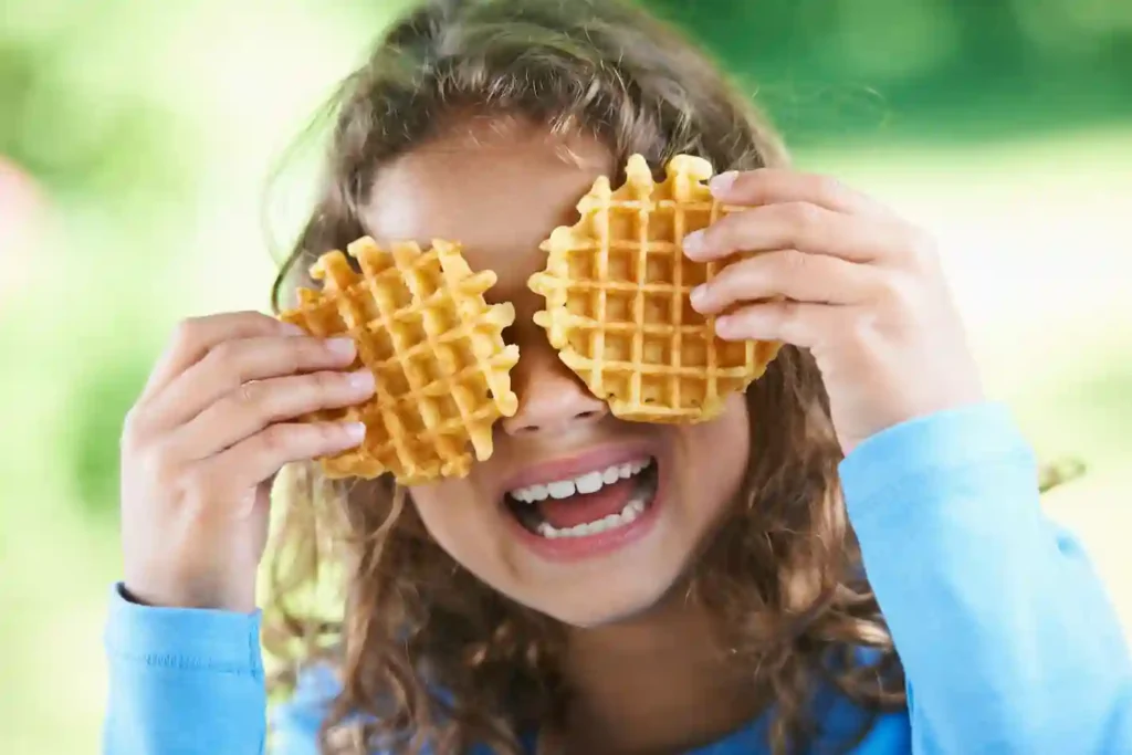 Smiling girl playing with waffles