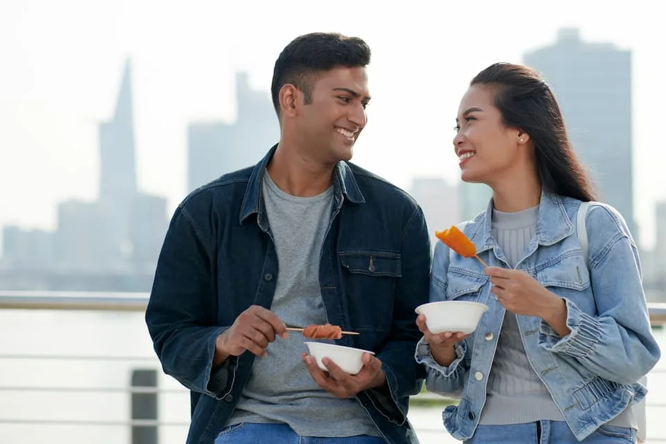 man and woman enjoying one of the popular street food, corn dogs - Chef's Deal