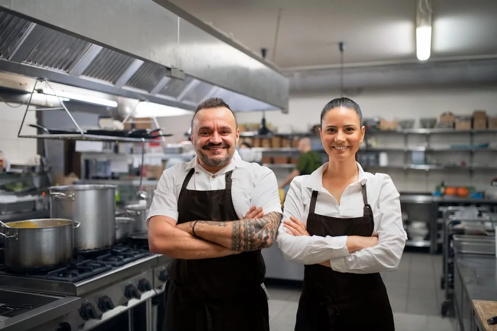 2 chefs are happy in their kitchen - A carefully arranged format can help retain employees, diminish time and product waste, and thus boost profits.