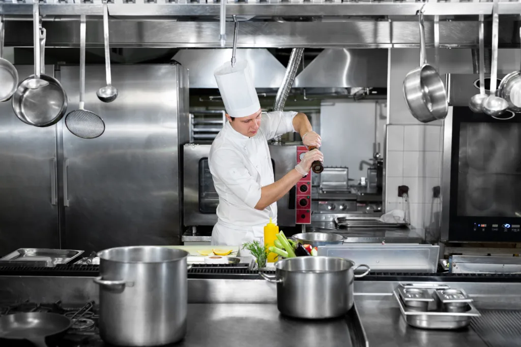 Chef is working in a restaurant kitchen - Aluminum vs stainless steel commercial kitchen equipment - Chef's Deal