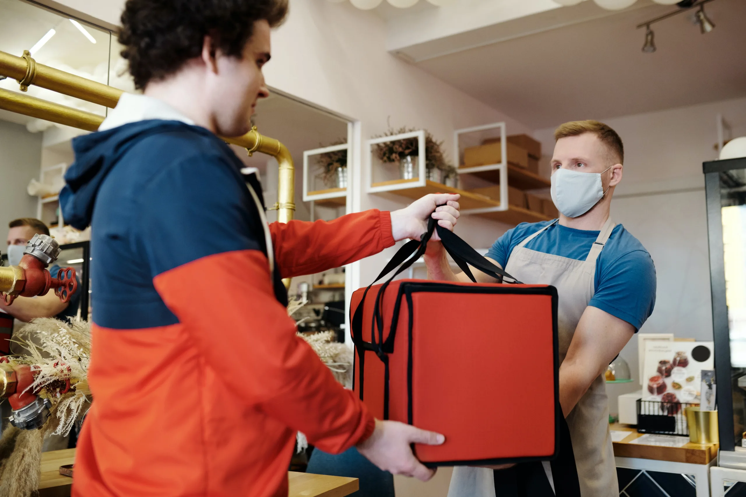 How to optimize a commercial kitchen for delivery and takeout? - Man handing an insulated bag to the delivery staff. 