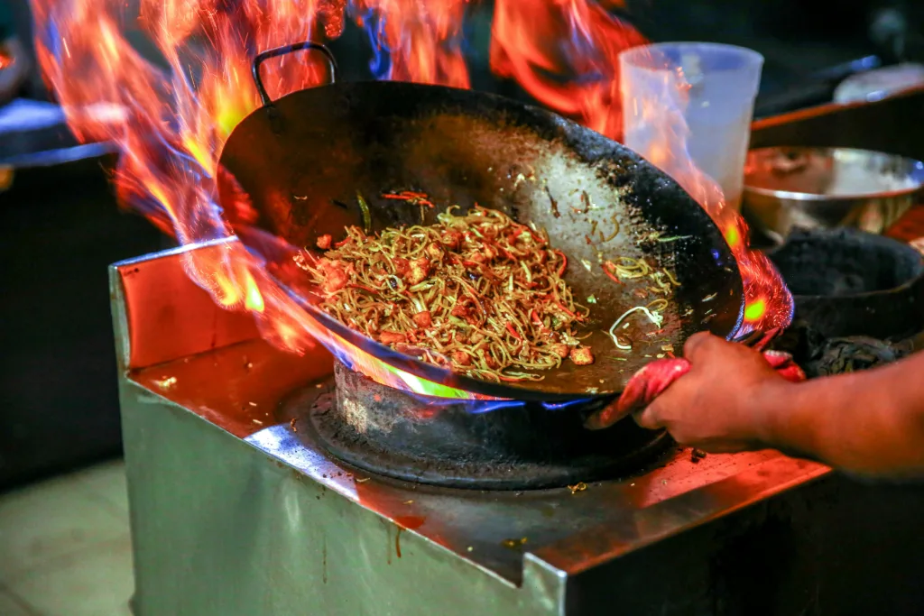 A person cooking on intense fire with little precautions - Restaurant Kitchen Safety Tips