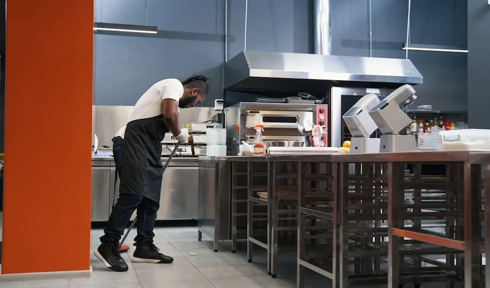 A young chef is cleaning the restaurant kitchen to prevent possbile slippng accidents. - Restaurant Kitchen Safety Tips