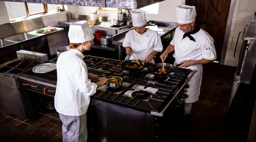 Chef's are preparing meals in a well-established kitchen setup.